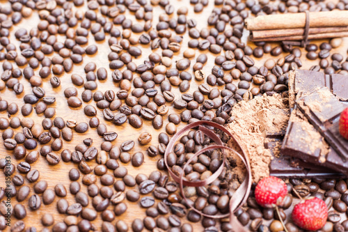 For holiday of chocolate day - wooden table background decorated a lot of coffee beans, chocolate bar, cacao, strawberries, cinnamon. Selective focus