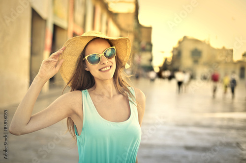 Smiling blonde girl wearing sunglasses and a big hat