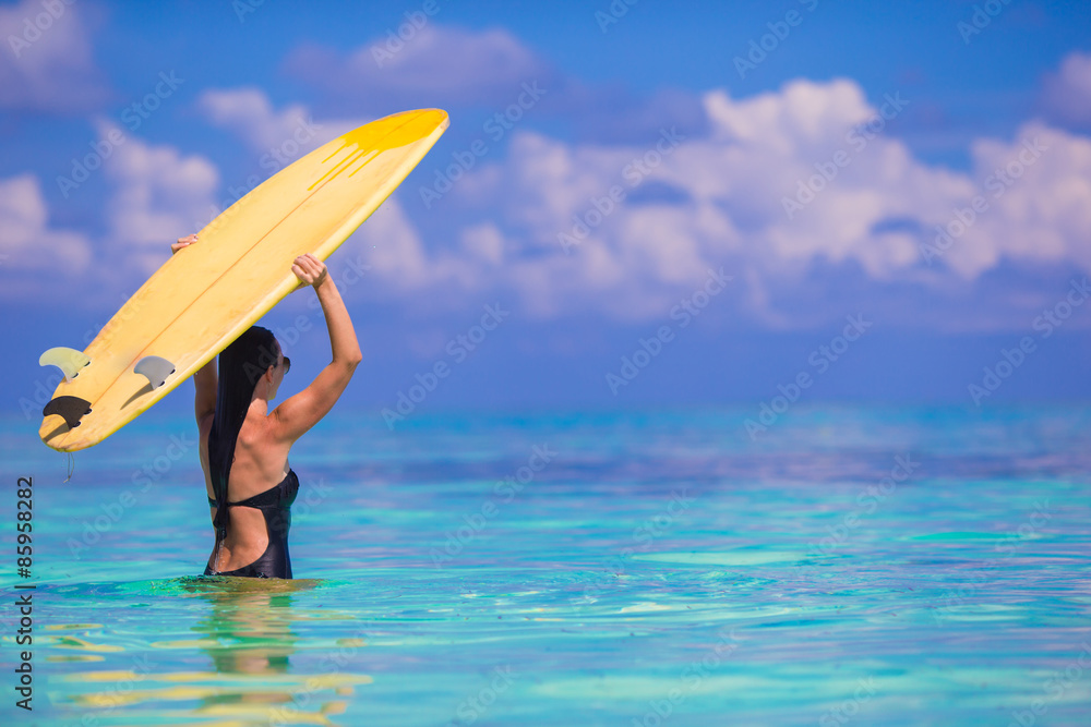 Happy shapely surf woman at white beach with yellow surfboard