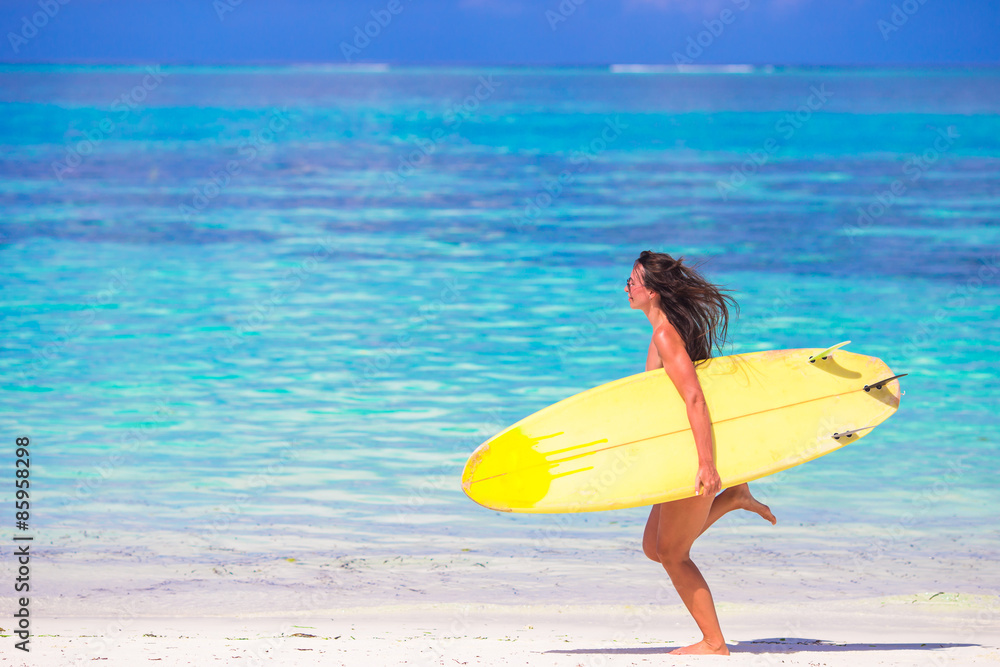 Happy shapely surf woman at white beach with yellow surfboard