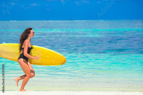 Happy shapely surf woman at white beach with yellow surfboard