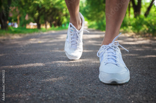 Cropped view of woman athlete running on pathway in park 