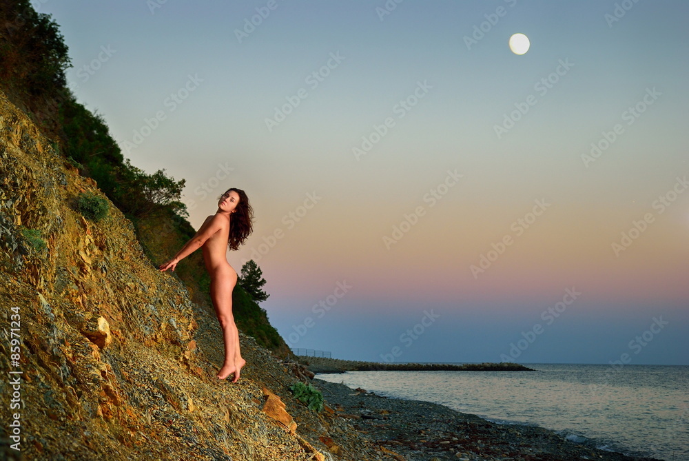 Nude girl walking on a rocky shore