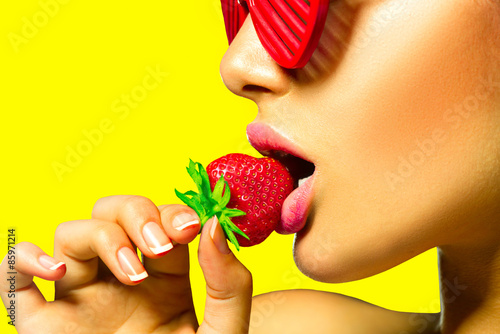 Obraz na płótnie Sexy woman wearing red glamor sunglasses eating strawberry