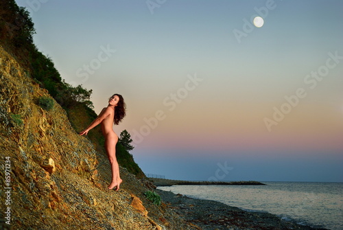 Nude girl walking on a rocky shore