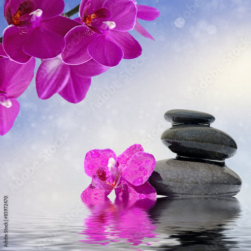 Zen spa concept background - Zen massage stones and orchid flowers reflected in water
