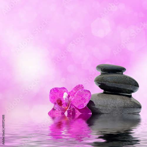 Zen spa concept background - Zen massage stones and orchid flowers reflected in water