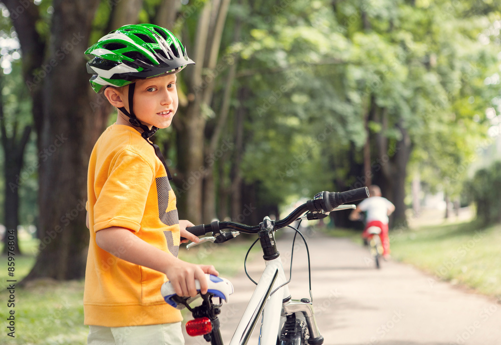 Boy in safe helmet with bicycle in city park Boy in safe helmet with bicycle in city park