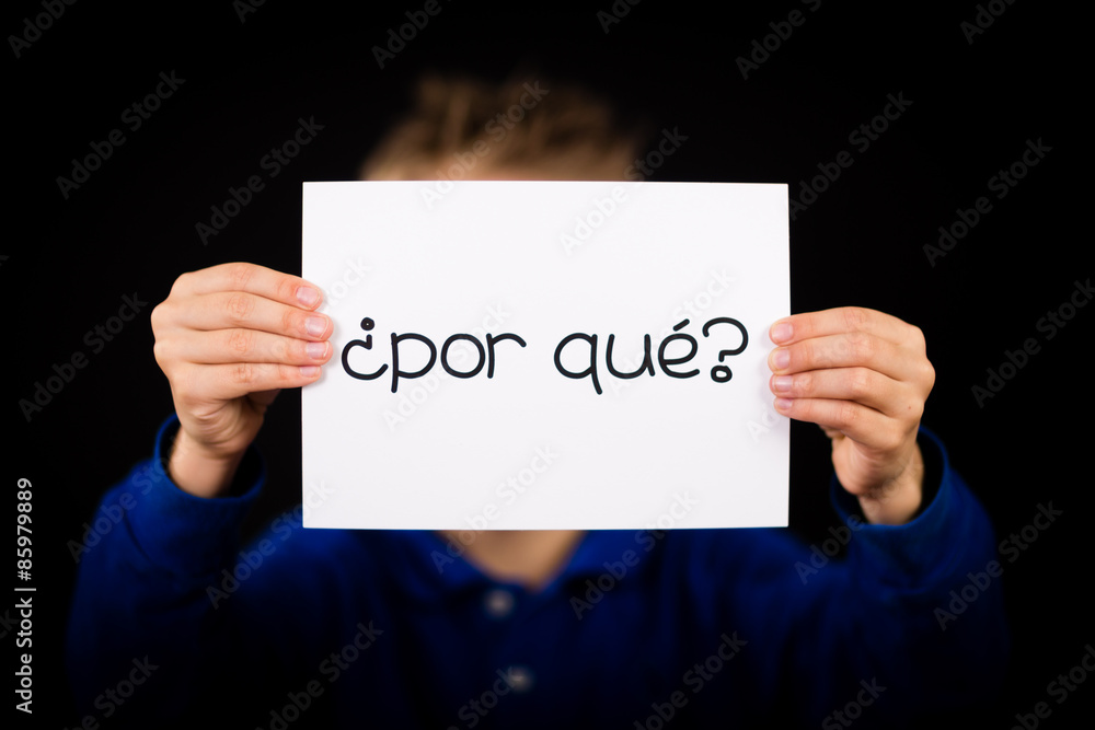 Child holding sign with Spanish words Por Que - Why Child holding sign with Spanish words Por Que - Why