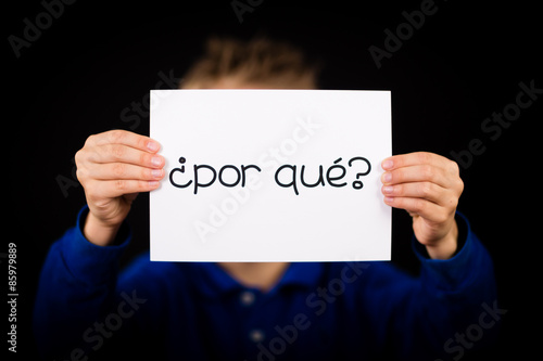 Child holding sign with Spanish words Por Que - Why