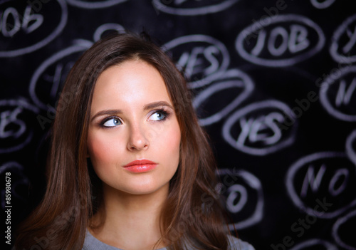 Thinking young woman with yes or no choice on grey background