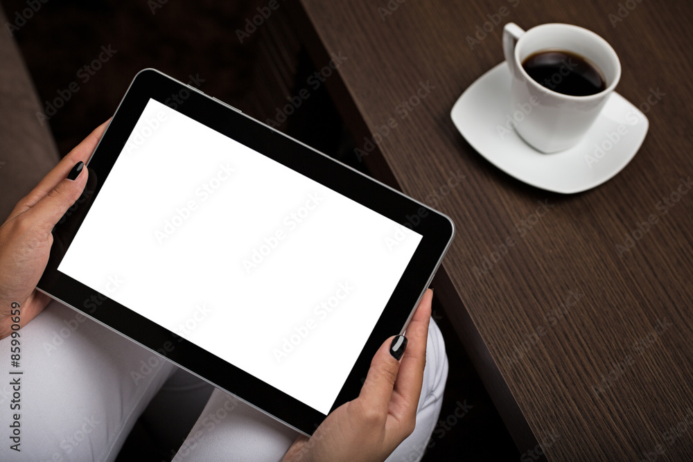 Someone holding digital tablet with blank screen next to table with cup of coffee. Someone holding digital tablet with blank screen next to table with cup of coffee.