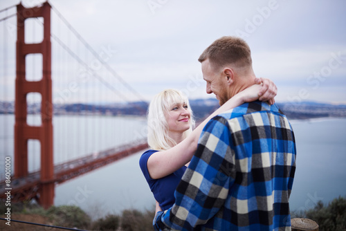 happy romantic couple in front of golden gate bridge on cloudy day