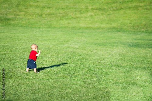 Little baby boy walking in a field.