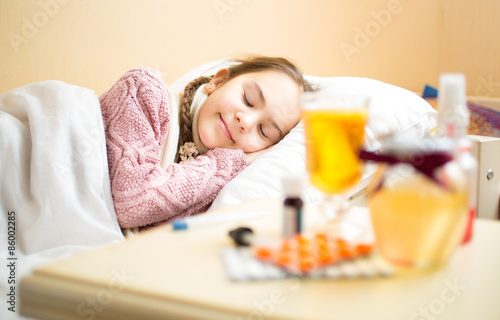 Portrait of sick girl in sweater lying in bed