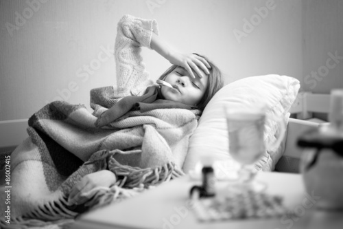 portrait of sick girl resting in bed and touching head