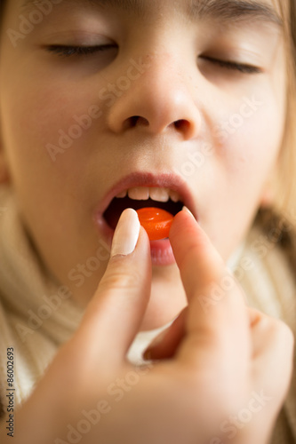 Closeup of sick girl putting pill on tongue