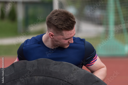 Young Man Doing Tire Flip Workout Outdoor