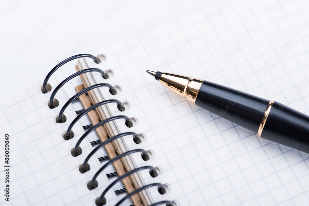 A spiral notebook with black ball pen over the white background, isolated A spiral notebook with black ball pen over the white background, isolated