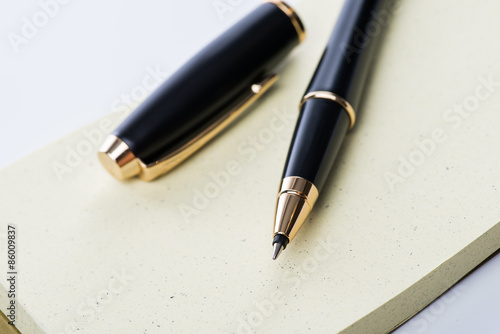 A spiral notebook with black ball pen over the white background, isolated