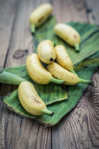 Golden bananas on the wooden floor with leaves. Vintage tone
