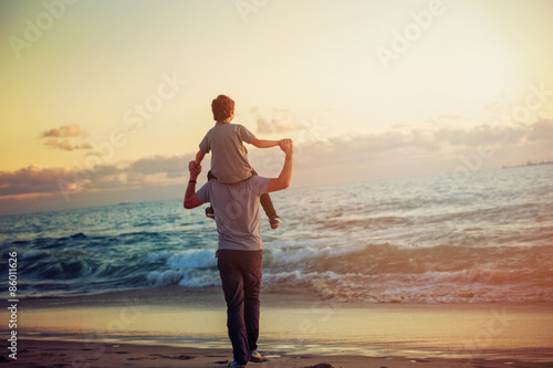 Happy father and son having great time on the beach in sunset