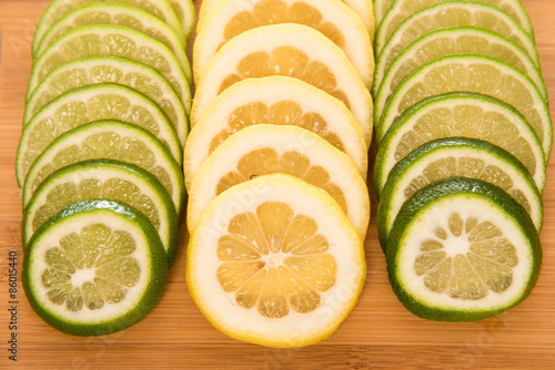 Fotografie Lemon and lime slices on a wood cutting board