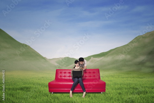 Couple using laptop on mountain landscape