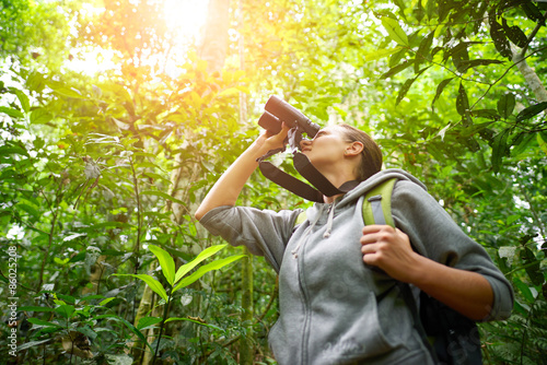 Young female hiker watching through binoculars wild birds