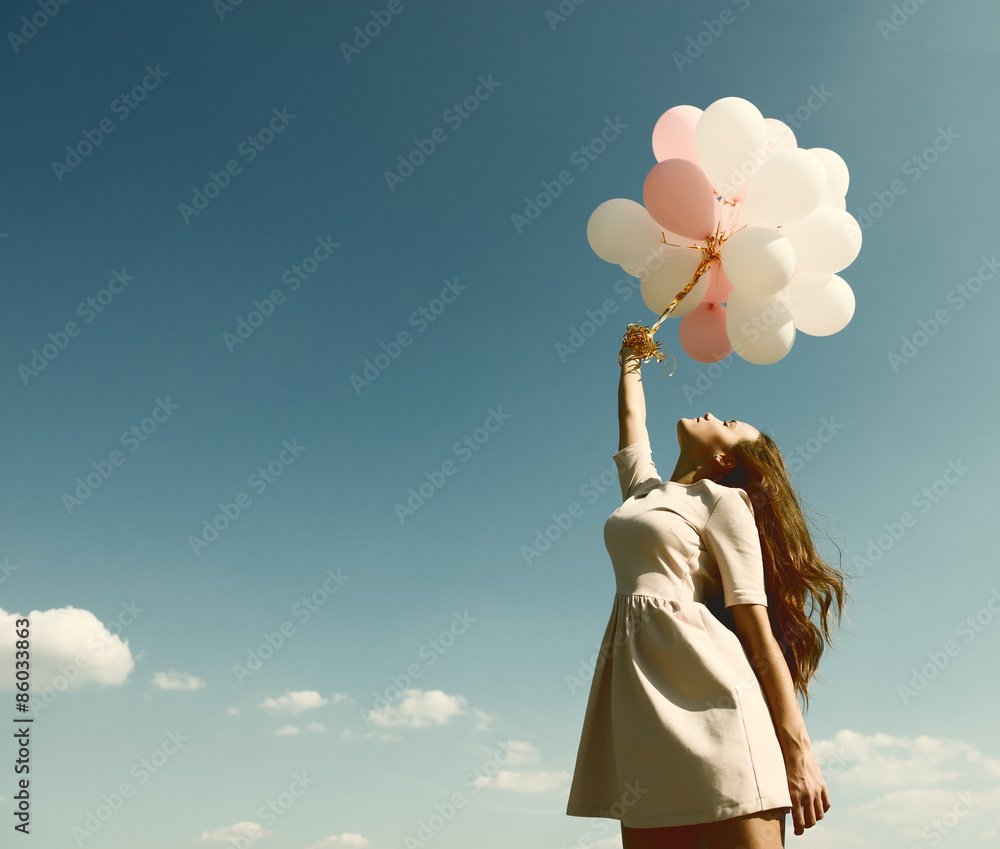 Fototapeta premium Fashion girl with air balloons over blue sky, toned.