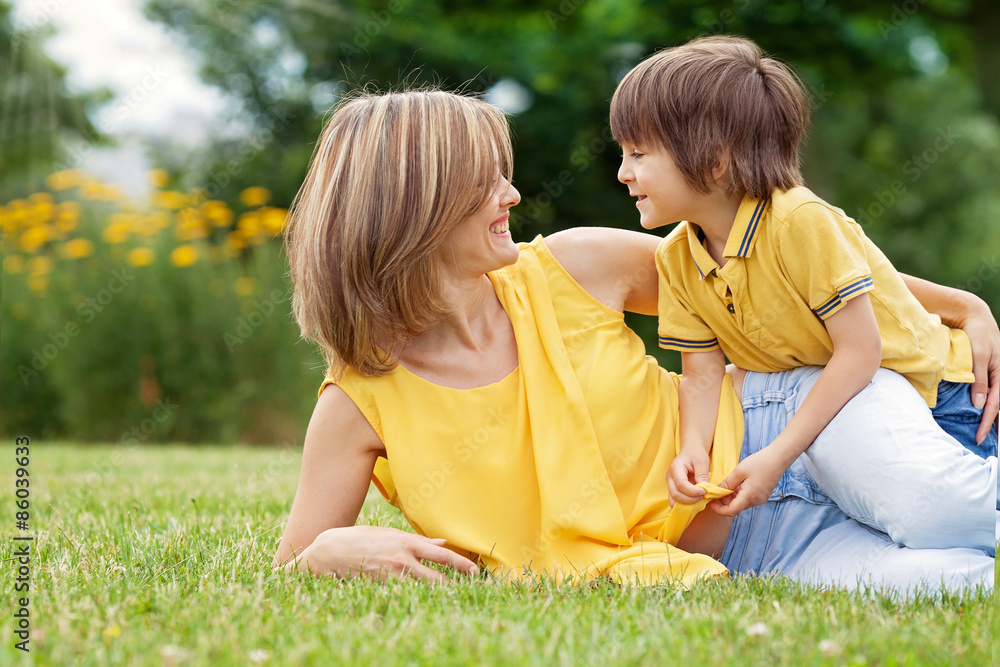 Fototapeta premium Young beautiful mom and her cute little boy, relaxing and having