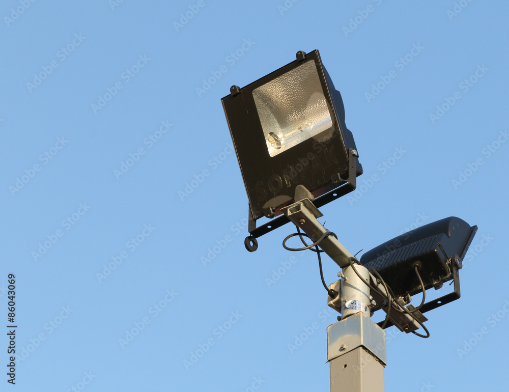 Security floodlights on a tall post against a winter blue sky Security floodlights on a tall post against a winter blue sky