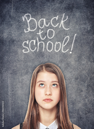 Teenage school girl looking up on the chalkboard background