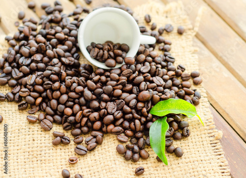 coffee beans with white cup and green leaves © elecstasy