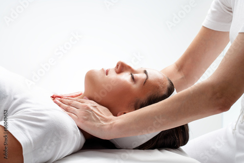 Therapist doing reiki on woman’s neck. photo