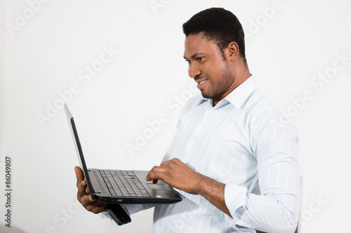 young man standing and working with a laptop.