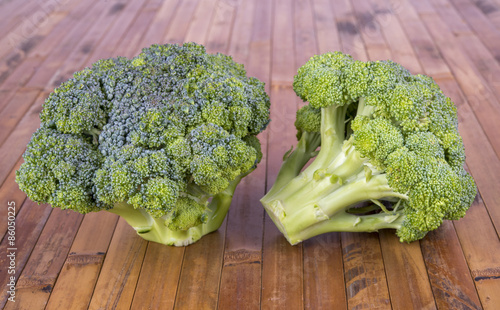 two fresh broccoli on a wooden surface