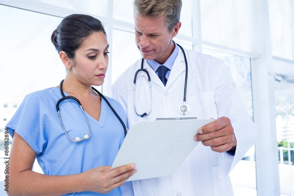Serious doctors looking at clipboard Serious doctors looking at clipboard