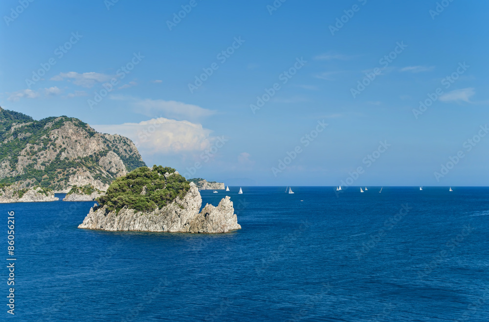 white sailboats in sea floating among rocky islands
