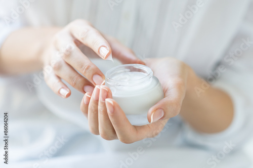 Beautiful woman hands applying moisturizer photo