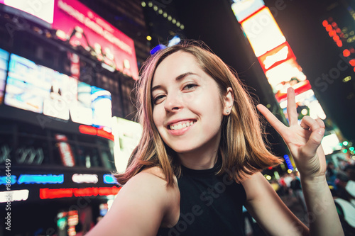 Young woman tourist takes selfie photo on Times Square, New York, USA