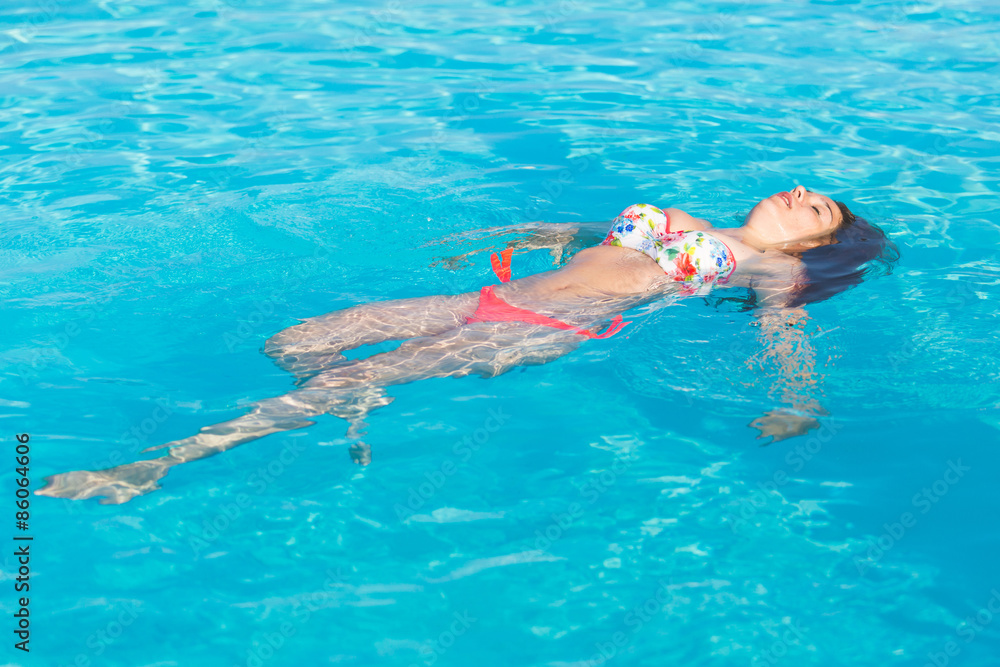 Beautiful woman lying on swimming pool water surface
