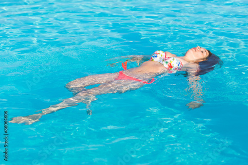 Beautiful woman lying on swimming pool water surface