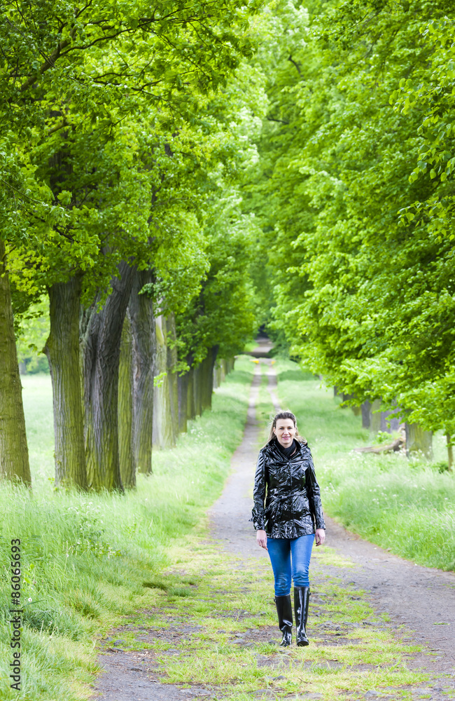woman wearing rubber boots walking in spring alley woman wearing rubber boots walking in spring alley