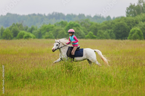 Foto Young rider galloping on horseback across the field Outdoors