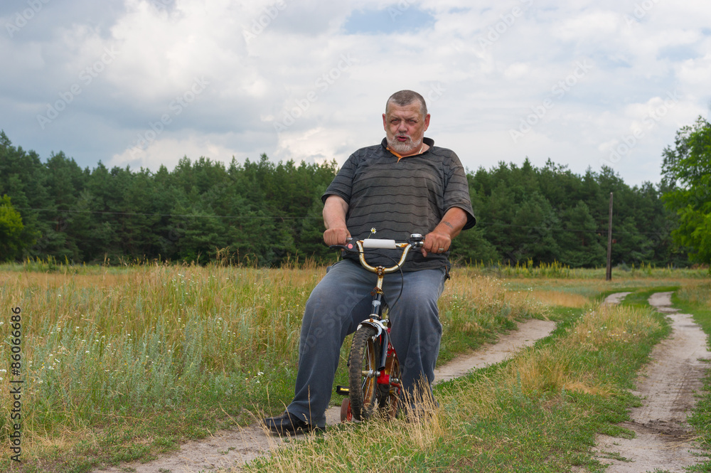 Old man playing with kids bicycle Old man playing with kids bicycle