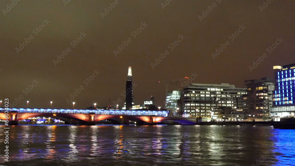 Getting far away from the bridge on London. Cruising along the Thames river can see some tall buildings at night Getting far away from the bridge on London. Cruising along the Thames river can see some tall buildings at night