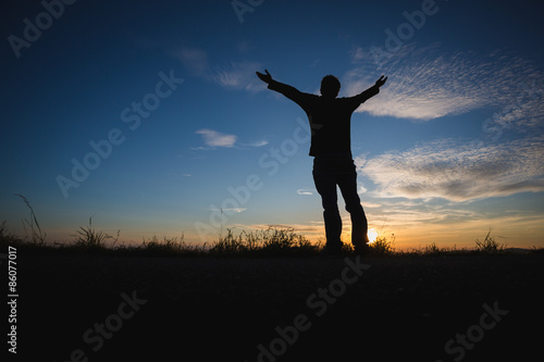 silhouetted man standing in sunset sky