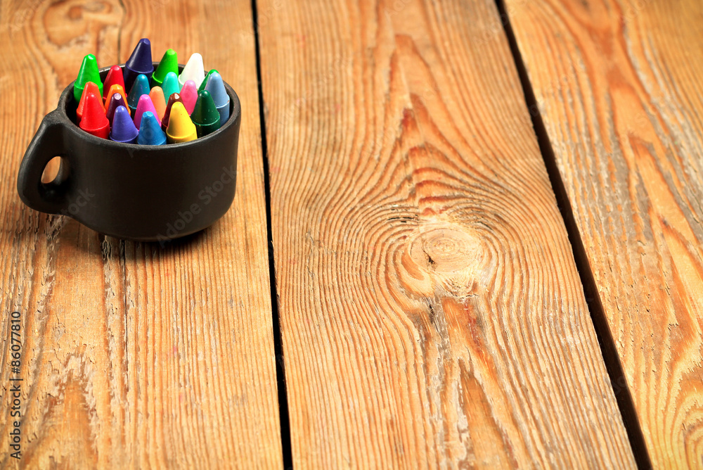 Naklejka premium Crayons in a mug on a wooden table