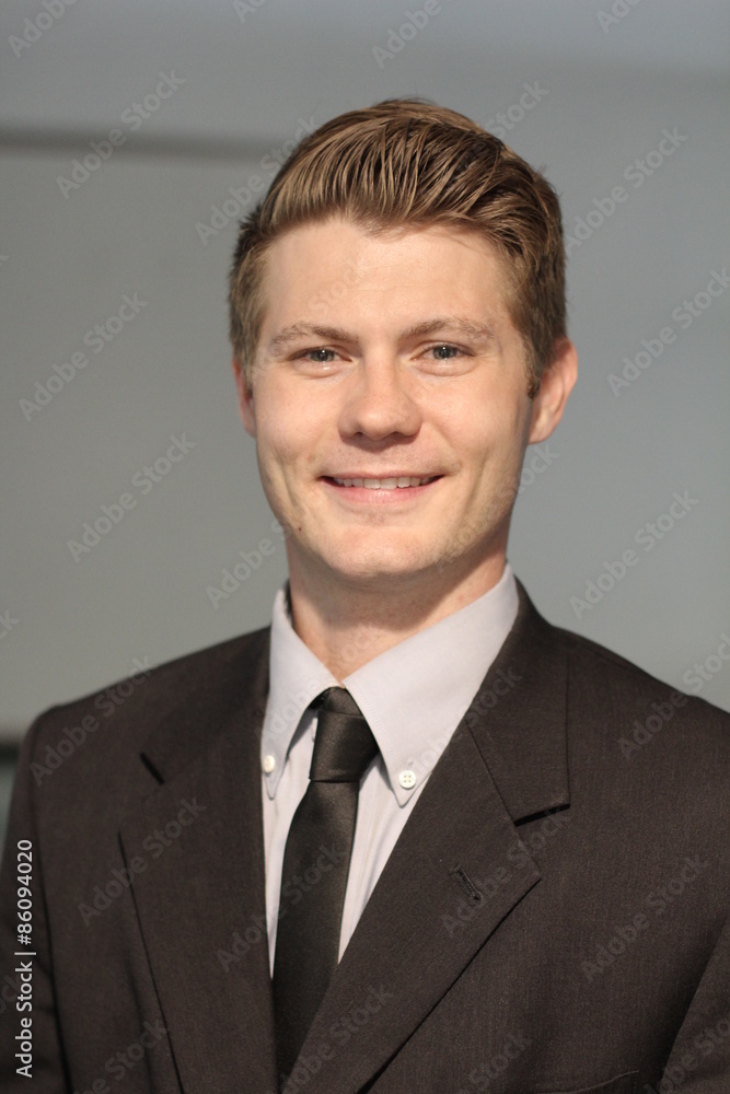 Portrait of a stylish young man standing posing in suit over modern interior background